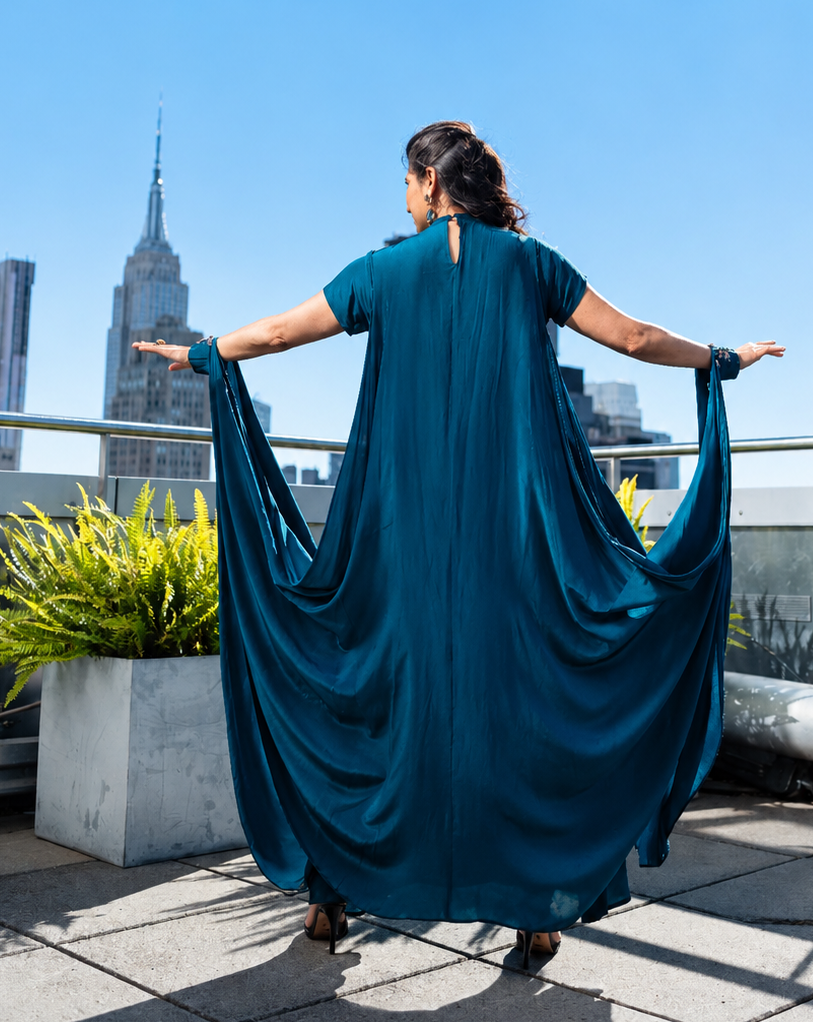 Person wearing a teal posh pari dress on a rooftop with city skyline in the background