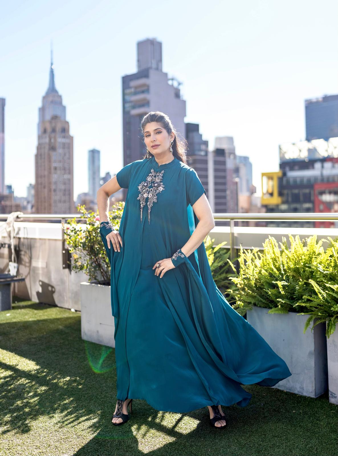 Woman in a teal posh pari gown dress standing on a nyc rooftop with city skyline in the background